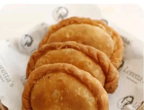 Three freshly fried Loretta's empanadas on wax paper